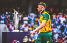 a man in green and yellow uniform standing next to a trophy