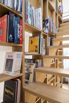 the bookshelf is filled with many books and there are wooden steps leading up to it