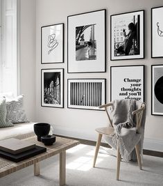 a living room with white walls and pictures on the wall, coffee table and chair