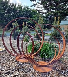 four circular metal sculptures sitting on top of dry grass