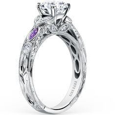 a white gold engagement ring with purple and white diamonds on the sides, surrounded by filigrees