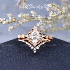 an engagement ring with a pear shaped diamond surrounded by small white and pink diamonds on top