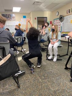 some people sitting in chairs and one is raising his hand