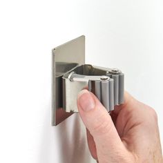 a hand holding a metal object on a white wall