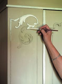 a man painting the side of a white cabinet