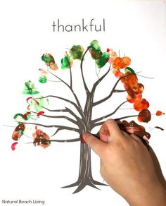 a hand is holding up a tree made out of paper and colored leaves with the words, thank you