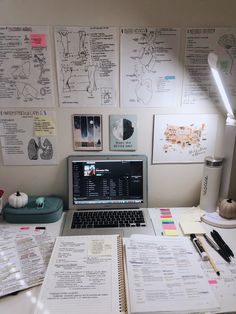 an open laptop computer sitting on top of a desk next to papers and other items