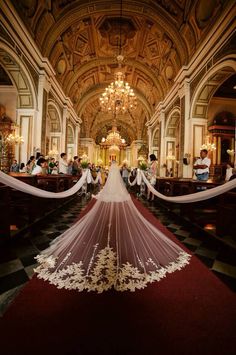 the bride is walking down the aisle with her long veil flowing in the wind at the end of the ceremony