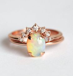 an opal and diamond ring on a white surface