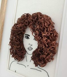 a drawing of a woman's face with curly hair on white paper in a frame