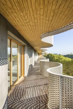 an outdoor balcony with wooden flooring and metal railings on the side of a building