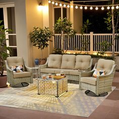 an outdoor living room with wicker furniture and string lights on the balcony area at night