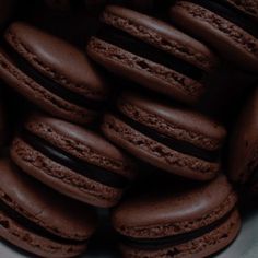 chocolate macaroons stacked on top of each other in a white bowl with black trim