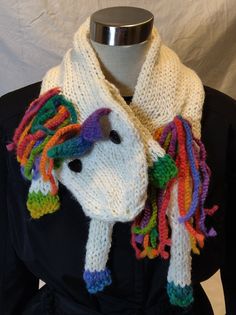 a knitted unicorn scarf with multicolored manes on it's head