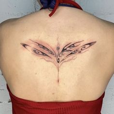 a woman wearing a red dress has a tattoo on her back that is shaped like two wings