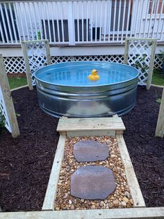 an outdoor hot tub in the middle of a yard with rocks and gravel around it