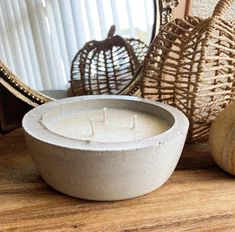 a white candle sitting on top of a wooden table next to a basket and mirror