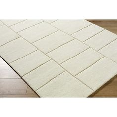 a large white rug on top of a wooden floor