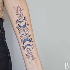 a woman with a tattoo on her arm that is decorated with flowers and crescents