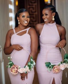 two women in pink dresses standing next to each other with flowers on their waists