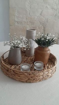 a wicker tray with candles and vases on it, sitting on a table