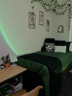 a bed with green sheets and pillows in a room next to a desk, chair and window