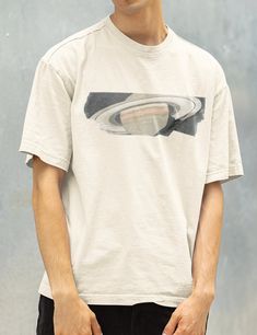 a young man wearing a white t - shirt with an image of a saturn on it