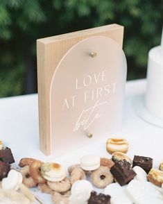 a wooden sign sitting on top of a table filled with donuts and marshmallows