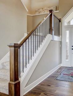 an entryway with stairs and rugs on the wooden floor next to white doors