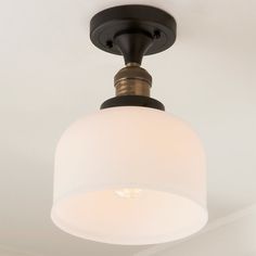 a light fixture with a white glass shade hanging from it's center point on the ceiling