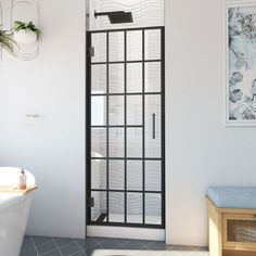 a bathroom with a white tub and black glass shower door next to a wooden bench