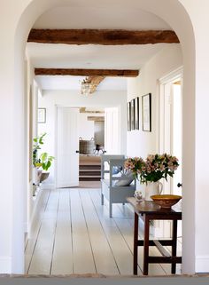 an archway leading to a living room and dining area with flowers in vases on the table