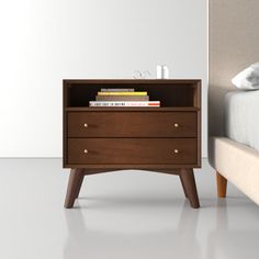 a nightstand with books on it next to a bed