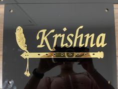 the reflection of a person holding a camera in front of a sign that says krshna