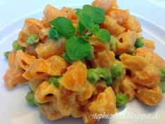 a white plate topped with macaroni and cheese covered in green garnish