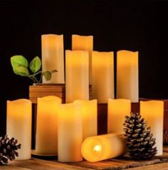 many lit candles on a wooden table with pine cones