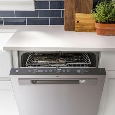 an empty dishwasher in a kitchen next to a potted plant on the counter