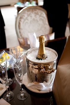 a bottle of champagne sitting on top of a table next to wine glasses and silverware