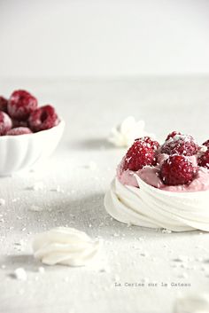 two small white bowls filled with whipped cream and raspberries on top of each other