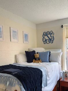 a teddy bear sitting on top of a bed in a room with pictures above it