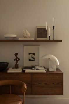 a shelf with books and candles on top of it next to a chair in a room