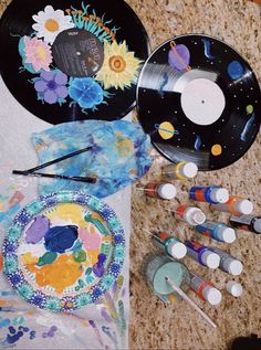 the table is covered with art supplies such as paper plates, paintbrushes and markers