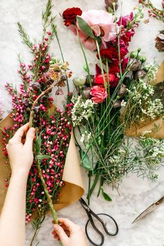 someone is cutting flowers with scissors on the table next to them and wrapping them in brown paper