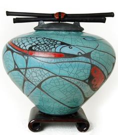 a blue vase with fish on it and two black sticks sticking out of the top