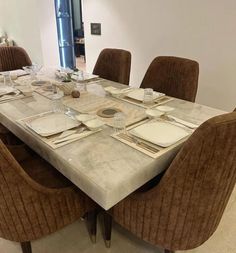 a dining room table set for six with place settings on the plates and napkins