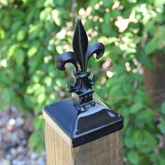 a black metal fleur de lis on top of a wooden post