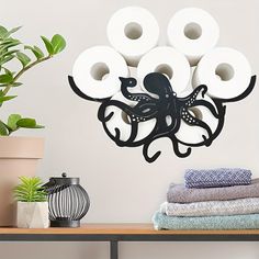 an octopus is hanging on the wall next to toilet paper rolls and a potted plant