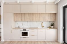 an empty kitchen with white cabinets and wood flooring on the walls, along with wooden floors