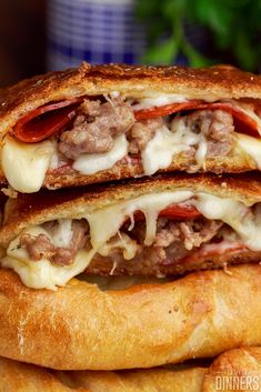 two sandwiches stacked on top of each other with meat, cheese and tomato slices in between