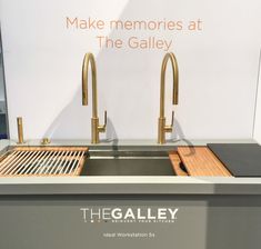 a stainless steel sink with two faucets in front of a sign that says make memories at the gallery